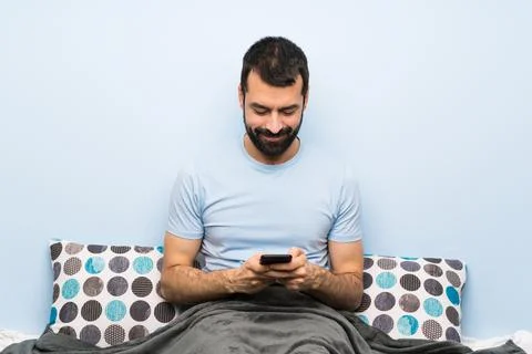 Man in bed sending a message with the mobile Stock Photos