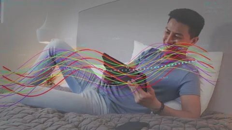 Man on bed tapping tablet starting waveforms sweeping across frame testing PHASE Stock Footage 333033777