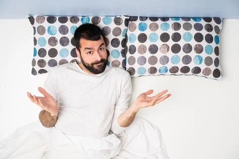 Man in bed in top view making doubts gesture Stock Photos