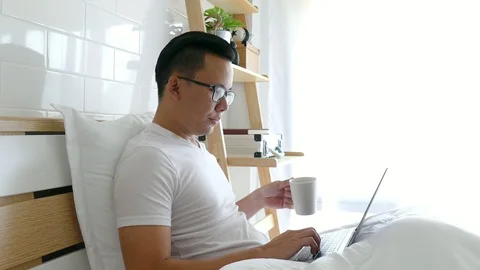 Man on bed is using his laptop to browse the web. Stock Footage 87016677