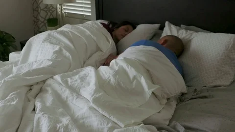 Man in bed waking up snoozing alarm clock on mobile phone at home 스톡 동영상 83189403