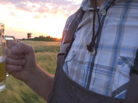 Man with beer in barley field on sunset Stock Footage