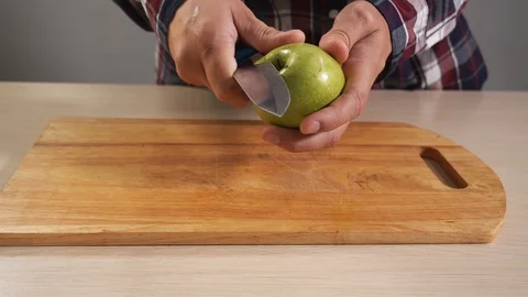 Man begins to clean fruit apple with knife in hand closeup from cajura 4K Stock Footage 119524714