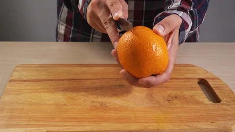 Man begins to clean orange with hand with knife closeup for healthy breakfast 4K Stock Footage 119521411