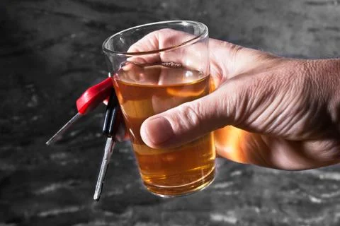 Man behind car key and glass of liqueur Stock Photos