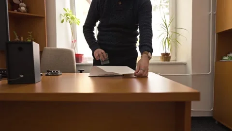 A man behind a desk looks through documents and stamps them for confirmation Stock Footage 330981860