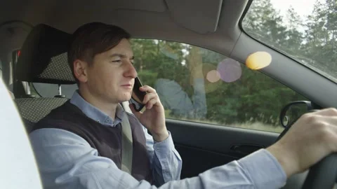 The man behind the wheel is talking on the phone, losing his balance. Sunny day Stock Footage 221689013