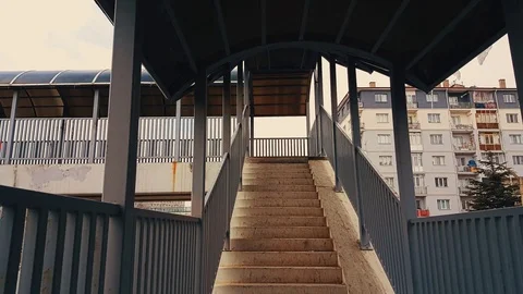 A man with beige coat and backpack walking up the stairs of the footbridge Stock-Footage 78383788