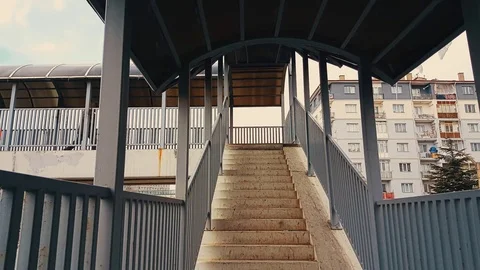 A man with beige coat running down the stairs of the footbridge Stock Footage 78382180
