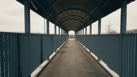 Man with beige coat walking across the footbridge over highway Stock Footage 78347984