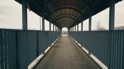 Man with beige coat walking across the footbridge over highway Stock Footage 78352019