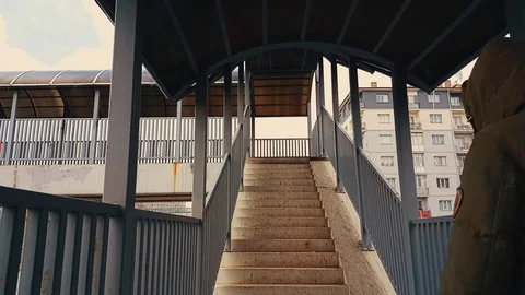 A man with beige coat walking up the stairs of the footbridge Stock Footage 78383076