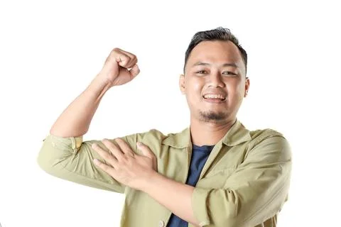 Man in beige jacket smiles flexing bicep with hand on arm on white Stock Photos