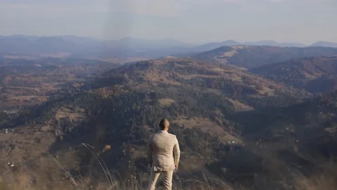 The man in beige suite standing in the mountains and thinks. back view Stock Footage 121324015