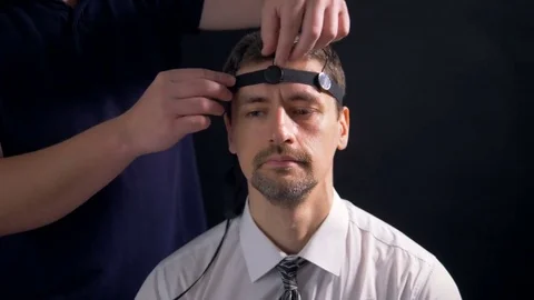 A man being fitted with polygraph head sensors. Video stock 76743033