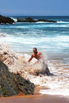 Man being splashed by a wave on the beach Stock Photos