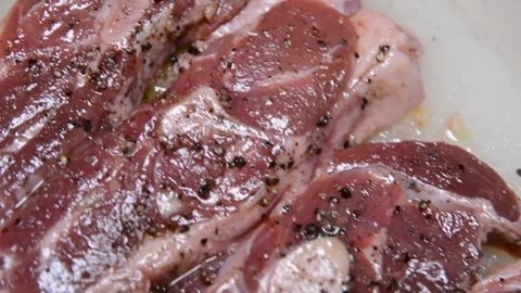 Man with belly sprinkles lamb meat with salt and pepper Stock Footage 130371883