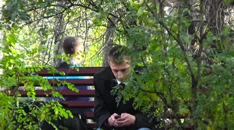 A man on a bench looking phone Stockbeeldmateriaal 54833197