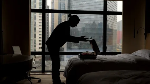 Man bend over bed, against lying suitcase, open it and stand still Stock Footage 102660290