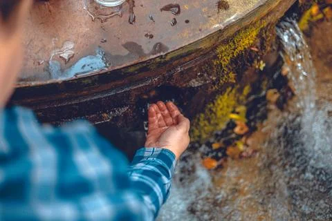 A man bent down to drink clean, cool water from a spring after a walk in the Stock-Fotos