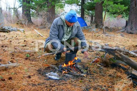 Man beside campfires in wood Stock Photos