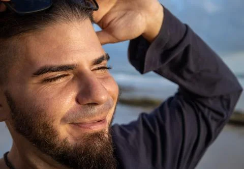 Man between 25 and 30 years old with a beard on the beach with a happy face. Stock Photos