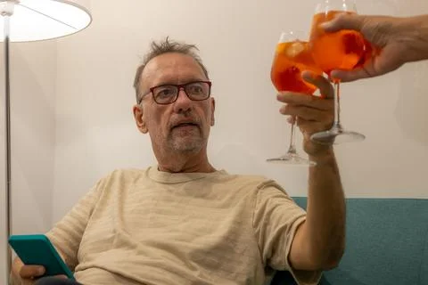 Man between 55 and 60 years old with a glass of orange drink toasting with .. Stock Photos