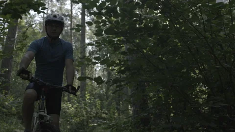 A man on a bicycle in the forest. A boy drives along a forest path at dawn Stock Footage 230234152