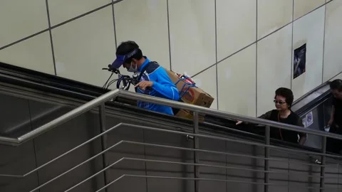 Man with bicycle going up escalator Видео 232836443