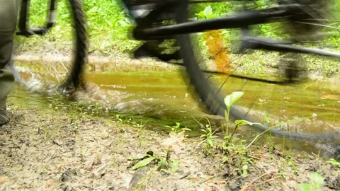 A man with a bicycle passing through a puddle Stock Footage 136094385