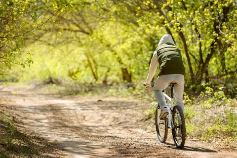 Man on bicycle rides through spring blooming park on sunny day Stock Photos
