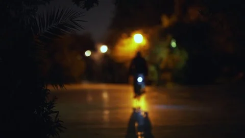 Man bicycling in dark empty scary park at night Stock Footage 73889978