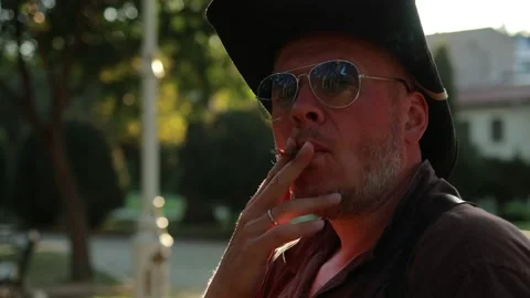 A man in a big hat smokes a cigar Stock Video Pond5