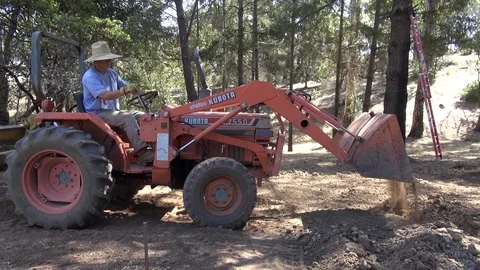 Man in big hat spreading dirt with Kobata digger, mid shot, HD Stock Footage 123546124