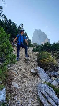 A man with a big hiking backpack going down a steep, narrow pathway Foto stock