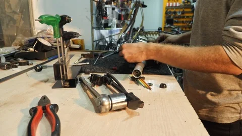 A man bike mechanic with a beard assembles a mountain bike in his workshop. Stock Footage 86469147