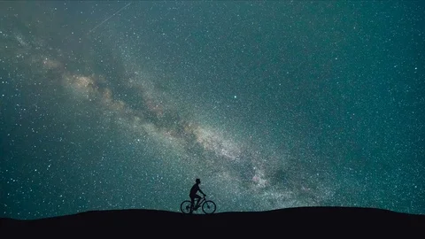 The man with a bike stand on a background of starry sky. night time, time lapse Stock Footage 82502736