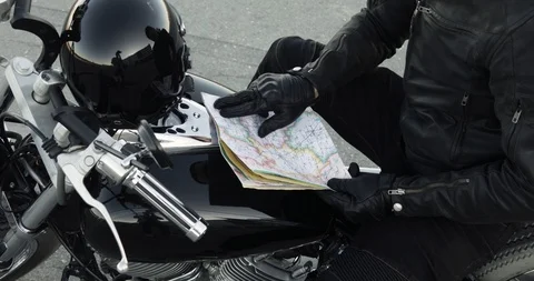 Man biker chooses the route on map sitting on his bike, hands closeup. Stockbeeldmateriaal 111997276