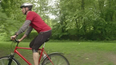 Man biking in a park Stock Footage 11340438