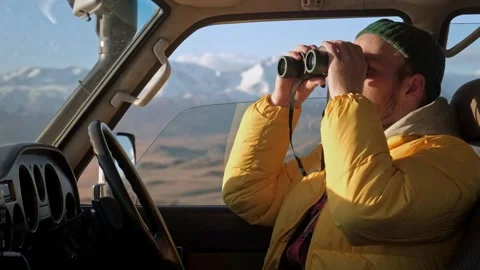 Man with binoculars in car looking through binocular searching for animal. Male Stock Footage 245556001