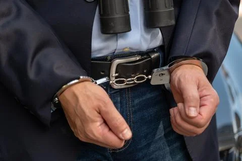 Man with binoculars is handcuffed after being detained for suspected illegal  写真素材