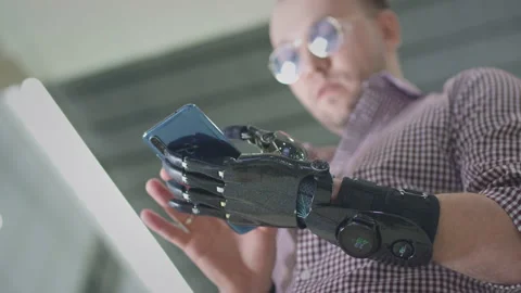 Man with a bionic futuristic arm uses smartphone. A male with a prosthetic hand Stock Footage 147860535