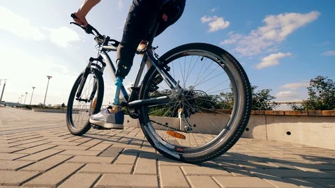 A man with a bionic leg is riding a bicycle outdoors Stock Footage 118613717