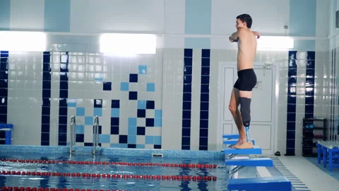 A man with a bionic leg is stretching muscles to jump into the pool 動画素材 99917317