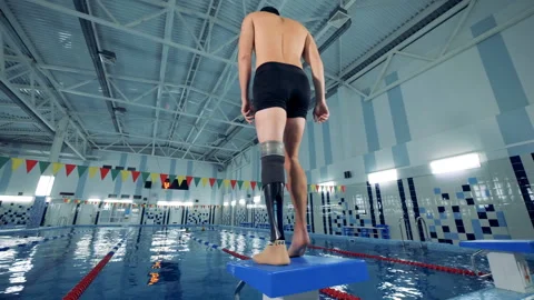 A man with a bionic leg is warming up in a swimming pool Stock Footage 99915700