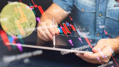Man Bitcoin  trading chart on the screen. Holding in hand a gold Bitcoin Cash Stock Photos