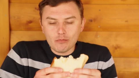 A man bites and eats a sandwich made of white bread. Stock Footage 154555705