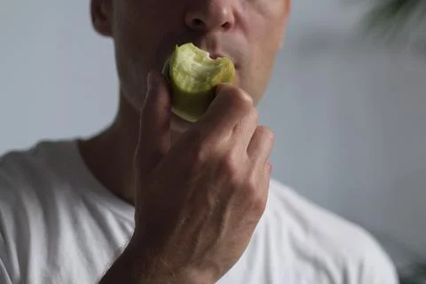 Man bites into an apple, capturing authentic texture and light. This minimalist Stock Photos