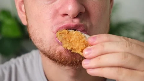 Man bites, chews fried chicken wing in breadcrumbs. man eats fast food Stock Footage 219732088