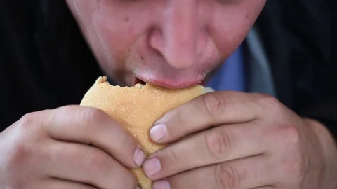 A man bites off a large piece of a sandwich with a cutlet Stock Footage 109416902